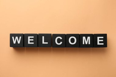 Kelime Hoş geldiniz bej arka planda siyah küplerden yapılmış, üst görünüm