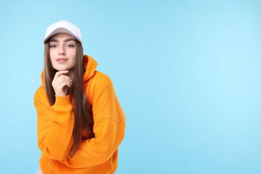 Açık mavi arka planda şık bir beyzbol şapkası takmış güzel bir kadının portresi. Metin için boşluk