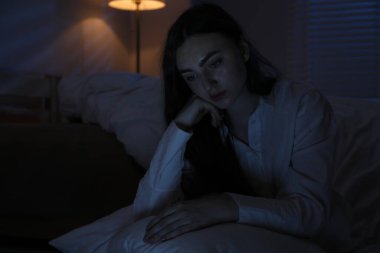 Evde uykusuzluk çeken, yastıklı, hayal kırıklığına uğramış bir kadın. Mesaj atmak için yer var.