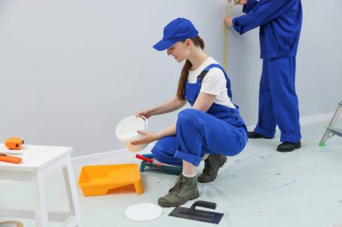 Farklı ekipmanlara sahip işçiler odayı yeniliyorlar.