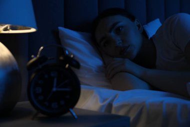 Evde yatakta uykusuzluk çeken hayal kırıklığına uğramış bir kadın.