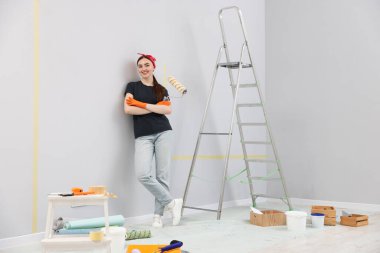 Odasında patenci, merdiven ve yenileme ekipmanı olan bir kadın var.