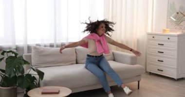 Mutlu arkadaşlar evdeki kanepede zıplayıp sarılıyorlar.