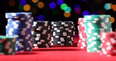 Kumarhane fişleri kırmızı masada bulanık ışıklara karşı, yakın plan. Kamera yakınlaştırılıyor