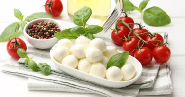 Beyaz ahşap masadaki çatallı mozzarella peyniri topunu alıyorum.