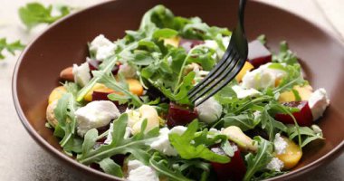 Gri masada roka ile lezzetli salata yiyorum, yakın plan.