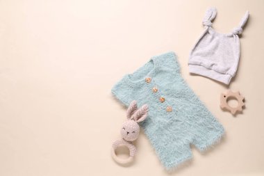 Bej arka planda bebek kıyafetleri ve aksesuarlar, düz yatış. Metin için boşluk