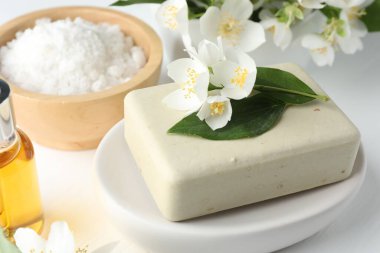 Sabun barı, deniz tuzu, temel yağ ve yasemin çiçekleri beyaz ahşap masada, yakın plan.