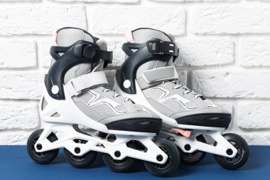 Beyaz tuğla duvarın yanındaki mavi masada bir çift paten.