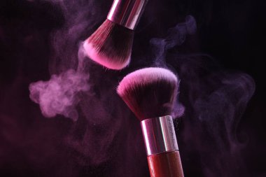 Renkli göz gölgeli makyaj fırçaları siyah arka planda neon ışıkları, yakın plan