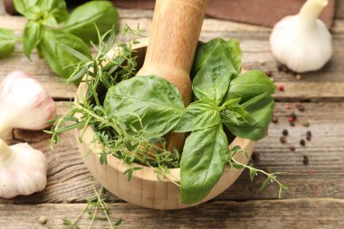 Kabuklu havan, farklı aromatik otlar ve baharatlar ahşap masada, yakın plan.