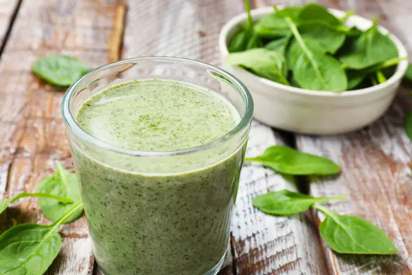 Lezzetli meyve püresi ve ıspanak yaprakları ahşap masada, yakın plan.
