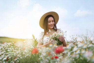 Gülen kadın şapkalı, papatya çiçekli yaban çiçeği çayırında