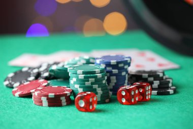 Kumarhane fişleri ve zarları yeşil masada bulanık ışıklara karşı, yakın plan