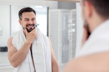 Banyoda aynaya bakarken tıraş olmadan önce gülümseyen adam.