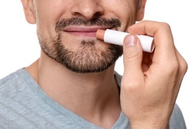 Beyaz arka planda dudaklarına dudak kremi süren adam, yakın plan.