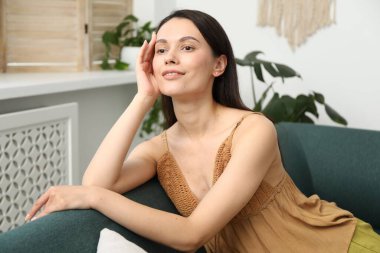 Uyum. Gülümseyen kadın evdeki kanepede dinleniyor.