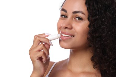 Gülümseyen kadın dudaklarına merhem sürüyor. Beyaz arka planda, yakın plan.