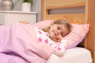 Küçük kız evde yatakta yatıyor.