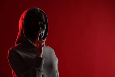 Anonimlik. Kırmızı arka planda maske takan kadın, metin için boşluk