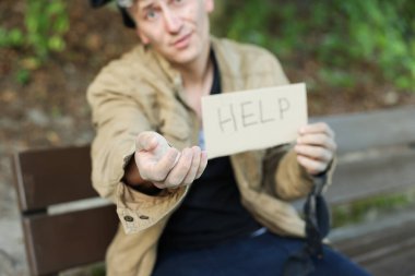 İşaretli evsiz adam Park bankında para dilenmeye yardım et, seçici odaklanma