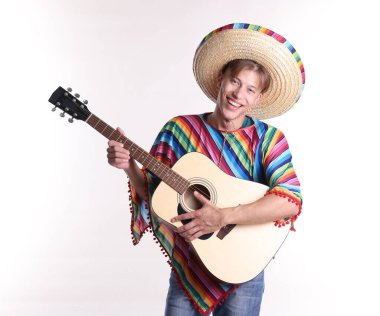 Sombrero şapkalı ve renkli pançolu gülümseyen adam beyaz arka planda gitar çalıyor.