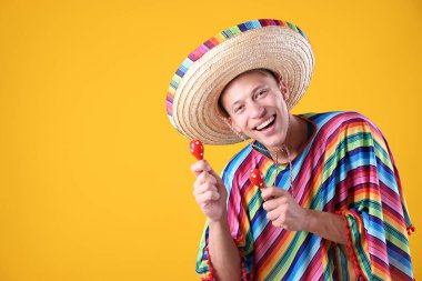 Şapkalı mutlu bir adam ve sarı arka planda marakas çalan renkli bir panço. Metin için boşluk