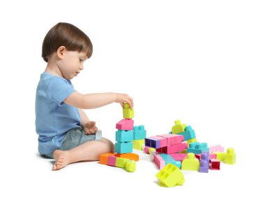 Beyaz arka planda tuğlalarla oynayan sevimli küçük çocuk.