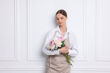 Beyaz duvarın yanında güzel şakayık demeti olan bir çiçekçi.