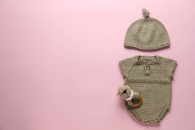 Pembe arka planda bebek kıyafetleri ve aksesuarlar, düz yatış. Metin için boşluk
