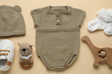 Bej arka planda bebek kıyafetleri ve aksesuarlar, düz yatış