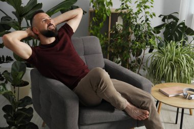 Uyum. Evdeki rahat koltukta dinlenen adam.