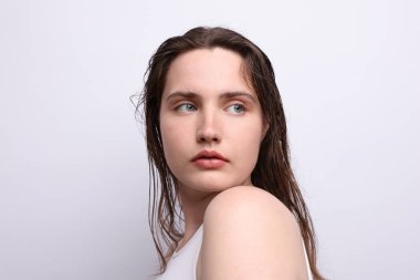 Açık gri arka planda doğal ten rengi olan güzel bir kadın, yakın plan.