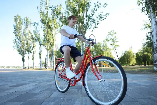 Şehir caddesinde bisiklete binen genç çocuk.