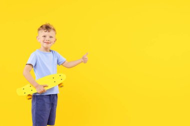 Para tahtalı küçük çocuk sarı arka planda baş parmak gösteriyor, mesaj için boşluk var.