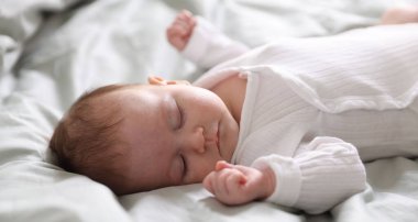 Sevimli yeni doğmuş bebek yatakta uyuyor, yakın plan.