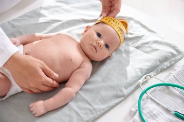 Klinikteki masada bantla bebeğin kafasını ölçen çocuk doktoru.