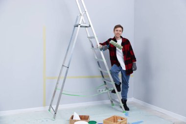 Odasında merdiven ve silindirli adam.