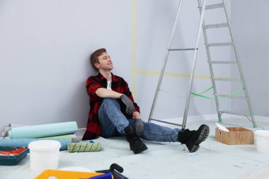 Odanın tadilatı sırasında yorgun bir adam mola veriyor.