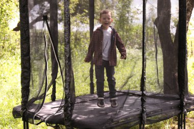 Küçük çocuk trambolinde eğleniyor.