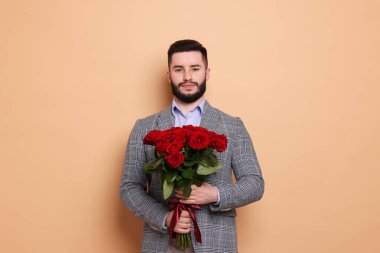 Bej arka planda kırmızı gül buketi olan adam.