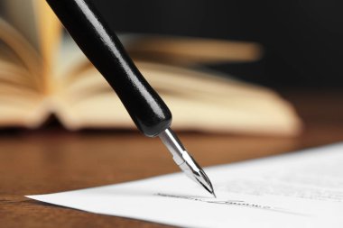 Siyah arkaplana karşı ahşap masadaki dolmakalemle noter belgesi imzalanması, kapatma