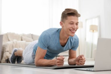 Evdeki koçla çevrimiçi derste tahta egzersizi yapan adam. Spor ve sağlıklı yaşam tarzı