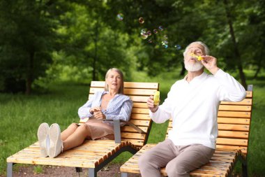 Güzel yaşlı çift parkta sabun köpüğüyle eğleniyor.