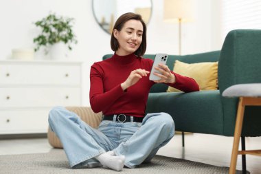 Evde modern akıllı telefon kullanan bir kadın.