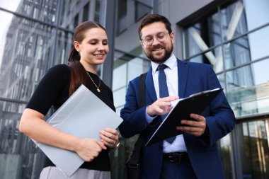 Mutlu iş arkadaşları ofis binasının yakınında düşük açılı bir şeyler tartışıyor.