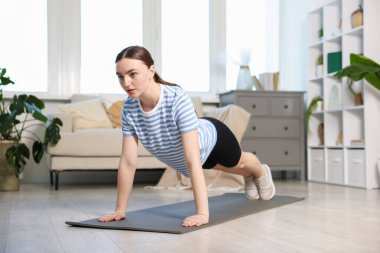 Sportif kadın evde kalas egzersizi yapıyor.