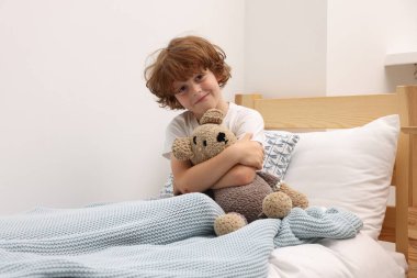 Oyuncak ayıyla evde küçük bir çocuk.