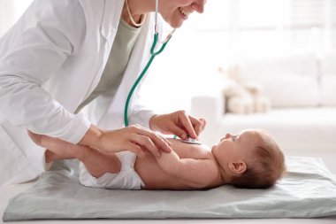 Klinikteki masada steteskopla bebeği muayene eden çocuk doktoru.