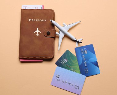 Uçak modeli, pasaport, uçuş bileti ve bej arka planda kredi kartları, düz konum